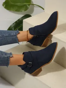 Detailed view of women's navy blue pointed-toe Chelsea boots with cross strap and buckle
