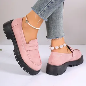 Close-up of pink suede loafers with thick black lug soles in British style
