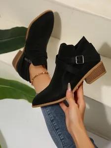 Detailed view of black pointed-toe Chelsea boots with cross straps and silver buckle
