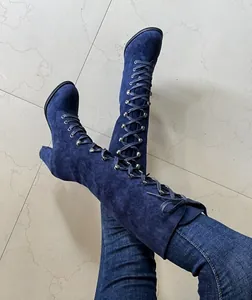 Close-up detail of blue suede lace-up knee-high boots with chunky heels and eyelets