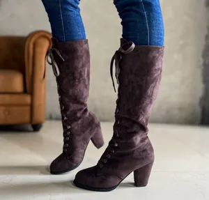 Detailed view of women's brown suede high-heeled lace-up tall boots worn on legs