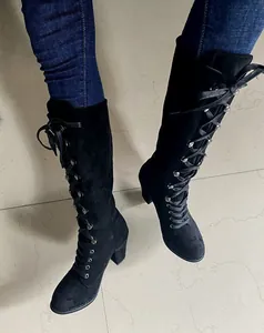 Detail view of black lace-up knight boots with chunky heels and silver eyelets.