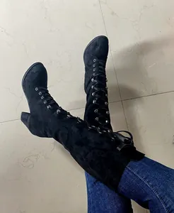 Close-up of stylish black suede lace-up boots featuring chunky high heels and round toe