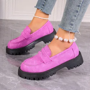 Detailed view of fashionable pink suede loafers with thick black platform soles worn on model