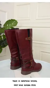 Close-up of burgundy faux leather knee-high rider boots with metal buckle detail