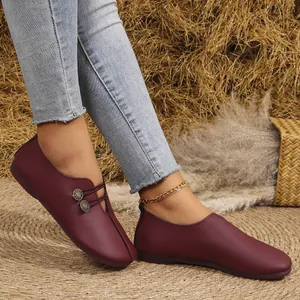 Primer plano de elegantes zapatos planos de cuero suave burdeos con botones decorativos