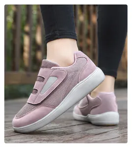 Detailed side view of mauve mesh walking shoes with velcro straps on wooden floor.