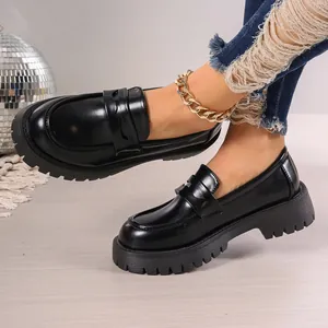 Close-up of black platform loafers with chunky serrated soles and gold anklet detail