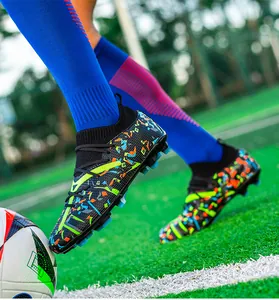 Close-up action shot of men's vibrant colorful soccer cleats with FG studs on turf
