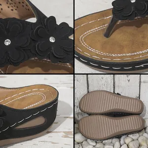 Detalle de sandalias negras de cuña con tres flores y detalles de pedrería para mujer