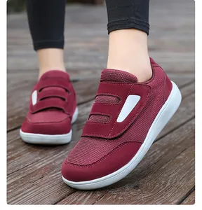 Detail view of burgundy mesh walking shoes with adjustable velcro straps on wooden floor.