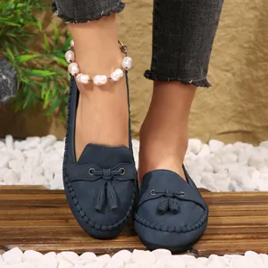 Detailed shot of navy blue women's suede loafers featuring tassel and pearl anklet.