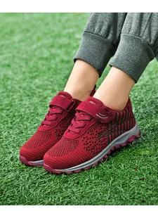 Detail shot of breathable red fly-woven sneakers being worn on green grass lawn