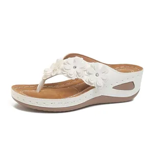 Vista lateral de chanclas blancas con cuña y tres elegantes adornos de flores