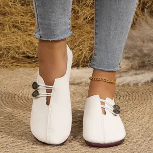 Detalle de zapatos planos de cuero suave blanco con botones decorativos y elásticos