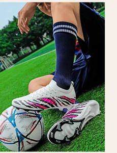 Gros plan de chaussures de football en tricot blanc avec rayures roses sur gazon
