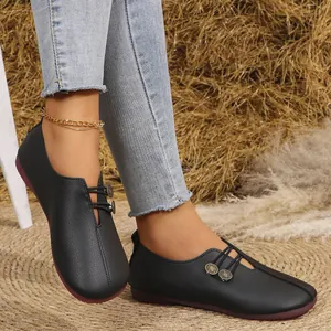 Primer plano de mocasines de cuero suave negro para mujer con botones y punta redonda
