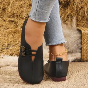 Vista detallada de mocasines planos de cuero suave negro con botones decorativos