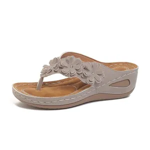 Vista lateral de chanclas con cuña para mujer con decoraciones florales y suelas gruesas.