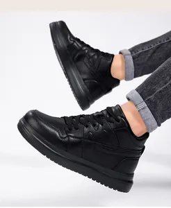 Close-up of black leather platform sneakers worn with grey jeans on white background