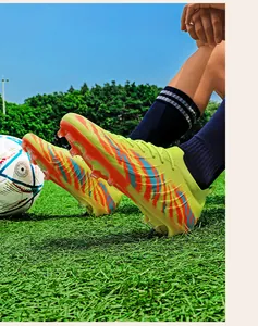 Crampons de football professionnels vert néon en fly-knit avec crampons AG sur le terrain d'herbe