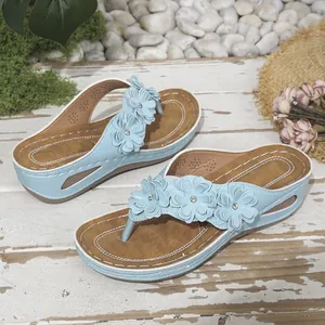 Vista detallada de chanclas de cuña azul claro con detalles de flores para verano