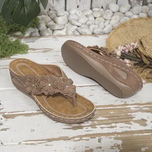 Vista detallada de chanclas de cuña marrones con tres flores y suelas gruesas