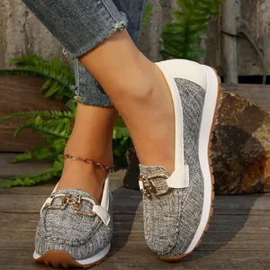 Primer plano de mocasines retro grises para mujer con hebilla dorada y suela de goma