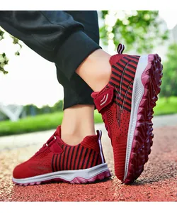 Close-up of red and black striped fly-knit athletic shoes being worn on a running track