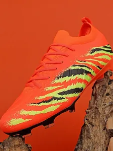 Chaussures de football professionnelles orange vif avec motif de rayures pour l'entraînement.