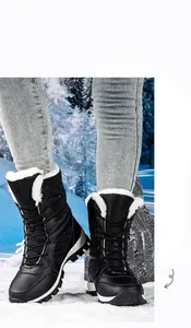 Black waterproof high-top snow boots with white plush lining in snow setting