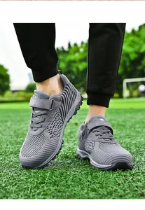 Close-up detail of grey flyknit mesh walking shoes on a vibrant green grass field