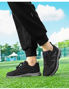 Men and women's black mesh outdoor walking shoes worn on a green grass field detail view