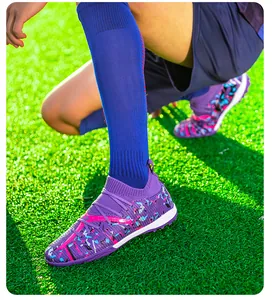 Detailed view of professional purple fly-knit soccer shoes on artificial green turf