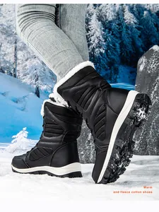 Close-up of black high-top fleece-lined women's snow boots in a winter outdoor setting.