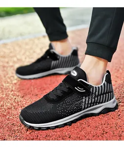 Close-up side view of black breathable flyknit mesh sneakers on a red track