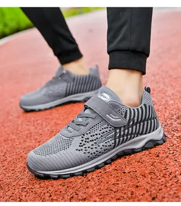 Breathable grey knitted walking shoes for men and women shown on a red running track