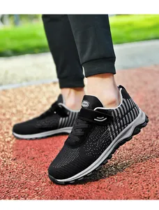 Close-up of black breathable mesh walking shoes on a red running track environment