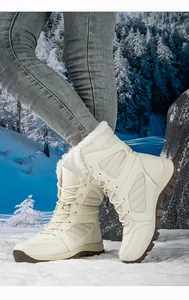 Close-up of white waterproof snow boots with faux fur lining on a snowy ground.