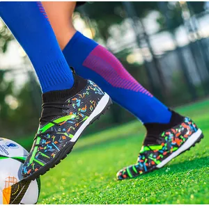 Macro view of colorful knit pattern on soccer cleats with TF turf sole on green field.