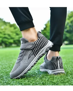 Detailed close-up of grey breathable knit walking shoes worn on a green grass field