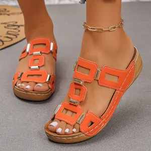Close-up of orange wedge slides with geometric cut-outs and metallic buckle details