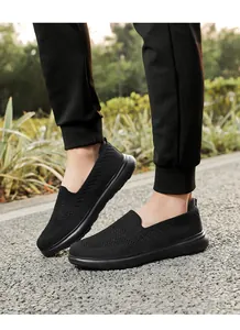 Detail of black fly-woven knit slip-on walking shoes worn by a person on a path