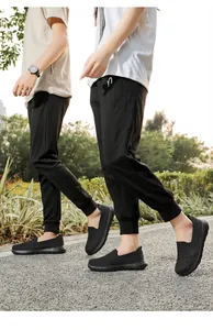 Two people wearing breathable black mesh fly-knit slip-on sneakers for outdoor walking.