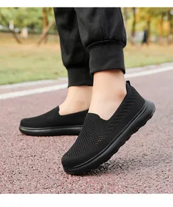 Detail view of black breathable fly-knit mesh slip-on walking shoes on a track