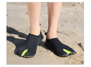 Close-up of breathable mesh split-toe water shoes worn on a sunny sandy beach