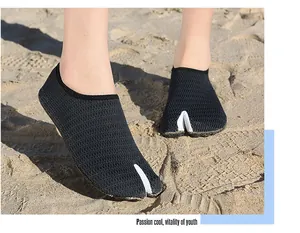 Close-up view of lightweight split-toe mesh water shoes worn on a sunny sandy beach