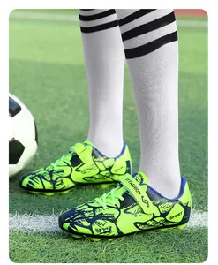 Vue détaillée de chaussures de football enfant vert néon avec velcro sur un terrain d'herbe