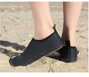 Close-up of black breathable mesh water shoes worn on a sandy beach for swimming.