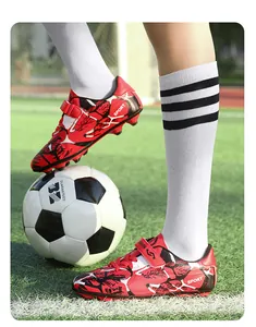 Gros plan de chaussures de football rouges pour enfants avec bandes velcro sur gazon